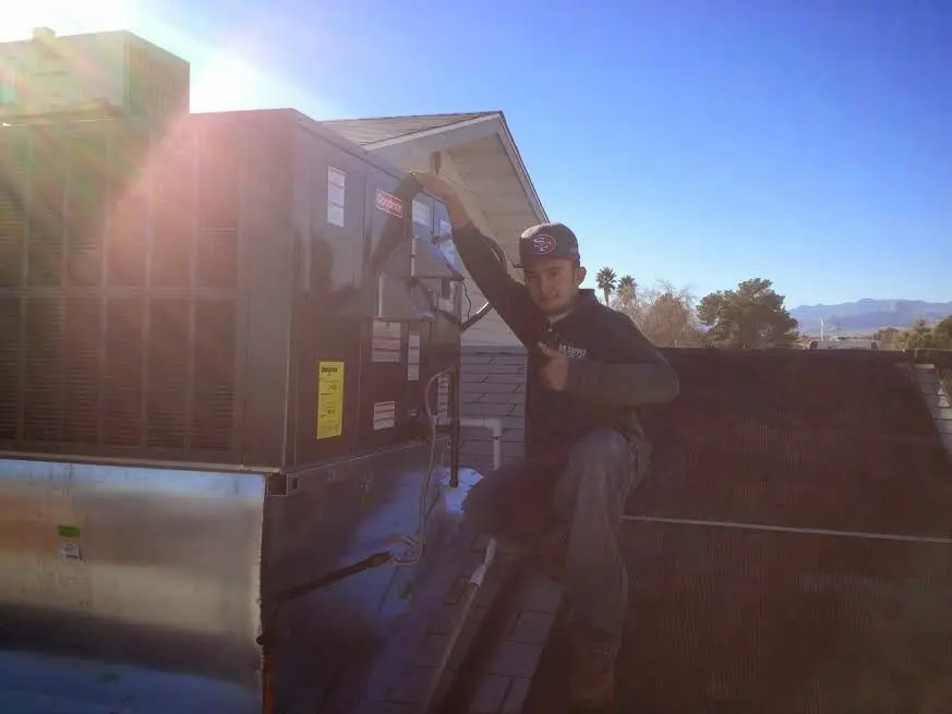 HVAC technician performing AC Tune-Up on a rooftop unit in Shafter